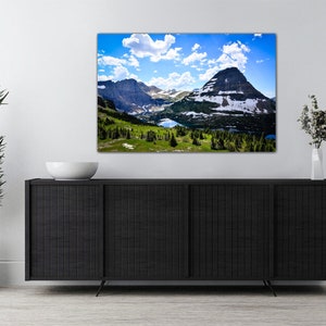 May include: A panoramic view of a mountain range with a lake in the foreground. The mountains are covered in snow and the sky is blue with white clouds.