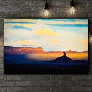 Pode incluir: Uma fotografia panor&acirc;mica de uma cena des&eacute;rtica com uma grande forma&ccedil;&atilde;o rochosa em primeiro plano. O c&eacute;u &eacute; de um azul vibrante com nuvens brancas e fofas. A forma&ccedil;&atilde;o rochosa &eacute; de cor marrom avermelhada e se destaca contra o p&ocirc;r do sol.
