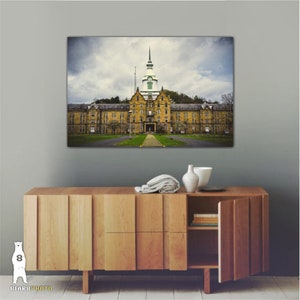 May include: A vintage photograph of a large, yellow brick building with a green roof and a clock tower. The building is surrounded by trees and grass. The photo is printed on canvas and ready to hang.