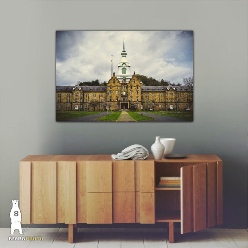 May include: A vintage photograph of a large, yellow brick building with a green roof and a clock tower. The building is surrounded by trees and grass. The photo is printed on canvas and ready to hang.