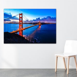 May include: A photograph of the Golden Gate Bridge in San Francisco, California. The bridge is lit up at night, and the water is calm and reflective. The sky is a deep blue, and there are clouds in the distance.