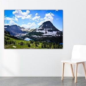 May include: A scenic landscape photograph featuring a mountain range with snow-capped peaks, a valley with a lake, and a blue sky with white clouds.