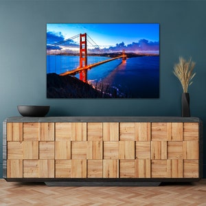 May include: A photograph of the Golden Gate Bridge in San Francisco, California. The bridge is lit up in the evening, and the water is calm and reflective. The sky is a deep blue, and there are clouds in the distance.