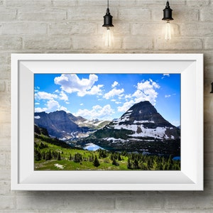 May include: A framed photograph of a mountain range with a blue sky and white clouds. The mountains are covered in snow and green trees. A lake is visible in the valley.