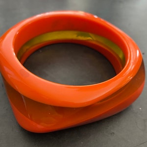Op de afbeelding: Oranje en bruine plastic armband met een gele binnenband.