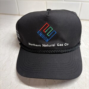 Pu&ograve; includere: Cappellino da baseball nero con il logo Enron ricamato in rosso, verde e blu. Il testo "Northern Natural Gas Co" &egrave; ricamato in bianco. Il cappellino ha un dettaglio di corda nera lungo la tesa.