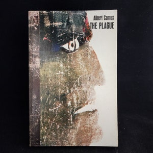 Può includere: Una copertina di libro con un primo piano di un occhio e parte del viso di una persona. Il libro è intitolato "La Peste" di Albert Camus.