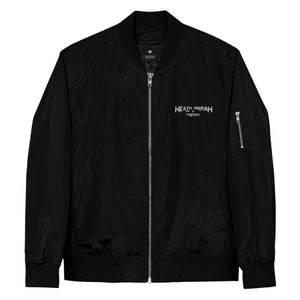 May include: Black bomber jacket with a zipper closure and a white embroidered logo that reads "HEATH + HANNAH FRIENDS".
