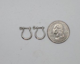 May include: Two silver earring hooks with a screw-on closure. The earrings are about the size of a US quarter.