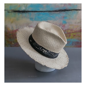 May include: A light brown straw hat with a black band and frayed edges. The band has white text that reads "Tokyo - Japan".