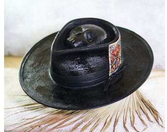 May include: A black fedora hat with a skull design on the crown and a colorful patch on the side.