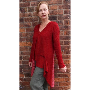May include: A red, long-sleeved, asymmetrical sweater with a V-neck and a textured knit. The sweater has a longer hem in the back and a shorter hem in the front.