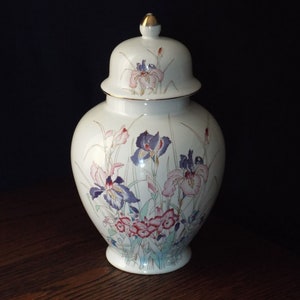 May include: White porcelain ginger jar with a lid, decorated with a floral pattern of pink, purple, and blue irises on a white background.
