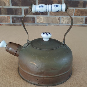 May include: A vintage copper tea kettle with a blue and white porcelain handle and lid. The kettle has a spout and a whistle.