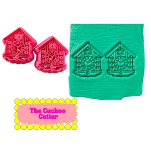 May include: Two pink cuckoo clock cookie cutters and a green clay impression of the same design. The cutters have detailed clock faces and house shapes. The text "The Cuckoo Cutter" is displayed on a pink background.