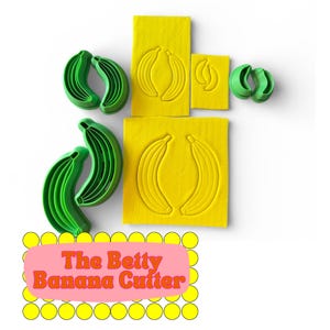 May include: A collection of green banana-shaped cookie cutters and yellow banana-shaped molds. The text "The Betty Banana Cutter" is displayed on a pink background with yellow circles.