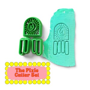 May include: A green plastic clay cutter set featuring an arched design with a crescent moon and star motif, accompanied by three separate rectangular cutters. A piece of light green textured clay shows the embossed impression of the cutter set.