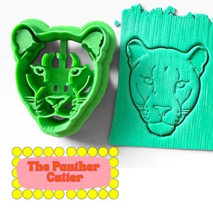 Könnte beinhalten: Ein hellgrüner, 3D-gedruckter Panther-Ausstecher neben einem passenden grünen Fondant-Abdruck, der das detaillierte Katzengesicht zeigt. Der Text The Panther Cutter ist in orangefarbenen Buchstaben auf einem rosa Hintergrund mit gelben Punkten zu sehen.