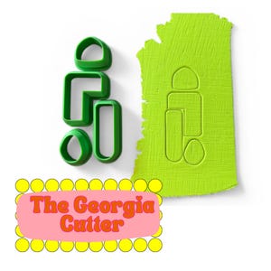 Könnte beinhalten: Grüne Plastik-Ausstecher in verschiedenen Formen, darunter eine Umrissform eines Staates und abstrakte Formen. Das Bild zeigt auch ein rosa Rechteck mit gelben Kreisen und dem Text "The Georgia Cutter".