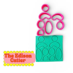 Könnte beinhalten: Eine Sammlung pinkfarbener Ausstecher in verschiedenen organischen Formen, darunter Kreise und Ovale, zusammen mit einem grünen Schaumstempel mit passenden Aussparungen. Der Text "The Edison Cutter" wird auf einem rosa und gelben Hintergrund angezeigt.