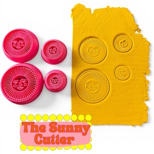 May include: A collection of pink, circular cutters with a sun face design, alongside a yellow clay slab with sun imprints. The text "The Sunny Cutter" is displayed in a pink banner with yellow circles.