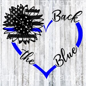 Puede incluir: Un girasol blanco y negro con una línea azul a través del centro. El girasol está dentro de un corazón azul con el texto "Back the Blue" escrito alrededor.