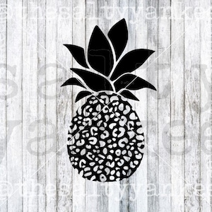 May include: Black and white pineapple with a leopard print design. The pineapple is on a white wood background.