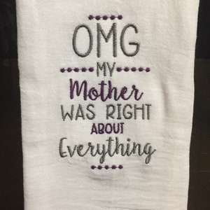 May include: White kitchen towel with purple and gray embroidery that reads "OMG MY MOTHER WAS RIGHT ABOUT EVERYTHING".