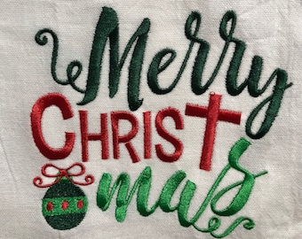 Puede incluir: Toalla de cocina blanca con texto bordado en verde y rojo que dice "Merry Christmas". Un adorno verde y rojo está bordado debajo del texto.
