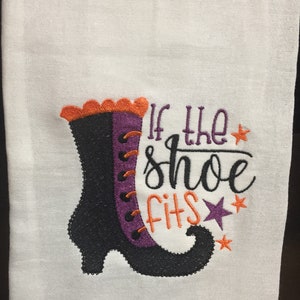 May include: White kitchen towel with an embroidered witch's boot and the text "If the shoe fits".