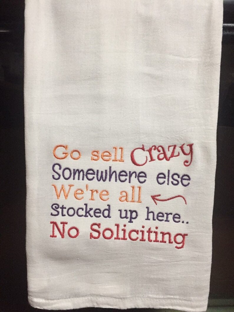 A humorous sign featuring a cartoon character, possibly a dog, stating 'Go Sell Crazy Somewhere Else We're All Stocked up Here No Soliciting.'