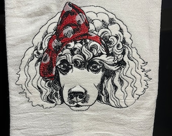 May include: A white kitchen towel with a black and white embroidered image of a poodle wearing a red bandana with white polka dots.