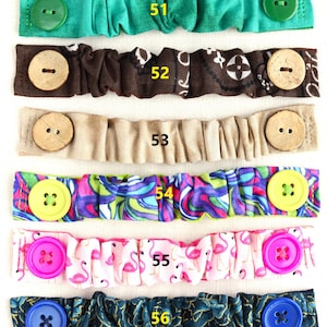 May include: Seven colorful fabric face mask extenders with different patterns and buttons. The extenders are numbered 50 through 57.