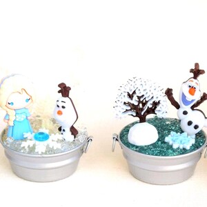 Pu&ograve; includere: Quattro scene decorative in miniatura in piccoli secchi d'argento. Ogni scena presenta personaggi del film Frozen, tra cui Olaf il pupazzo di neve, Elsa ed elementi a tema invernale. I secchi sono riempiti di glitter.