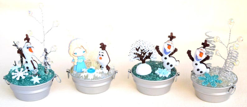 Pu&ograve; includere: Quattro scene decorative in miniatura in piccoli secchi d'argento. Ogni scena presenta personaggi del film Frozen, tra cui Olaf il pupazzo di neve, Elsa ed elementi a tema invernale. I secchi sono riempiti di glitter.