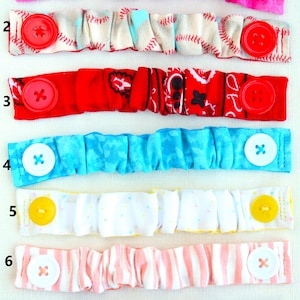May include: Seven different fabric mask extenders with various patterns and colours. Each extender has a button on each end. The extenders are numbered 1 through 7.