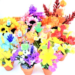 May include: A collection of colorful artificial flower arrangements in small terracotta pots. Each pot features a variety of flowers in shades of yellow, orange, red, purple, and blue, decorated with crayon and eraser-shaped accents.