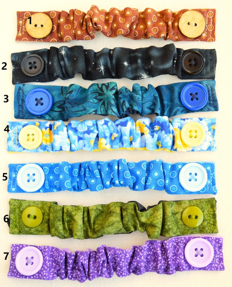 May include: Seven different fabric face mask extenders with various colors and patterns. Each extender has two buttons on either end. The extenders are numbered 1 through 7.