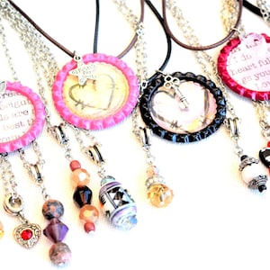 May include: A set of seven necklaces with bottle cap pendants. Each pendant has a different design and message. The necklaces are made with various chains and beads.
