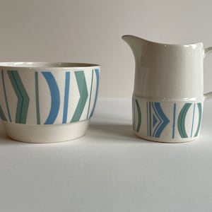 May include: A white ceramic sugar bowl and creamer set with a blue and green geometric pattern.