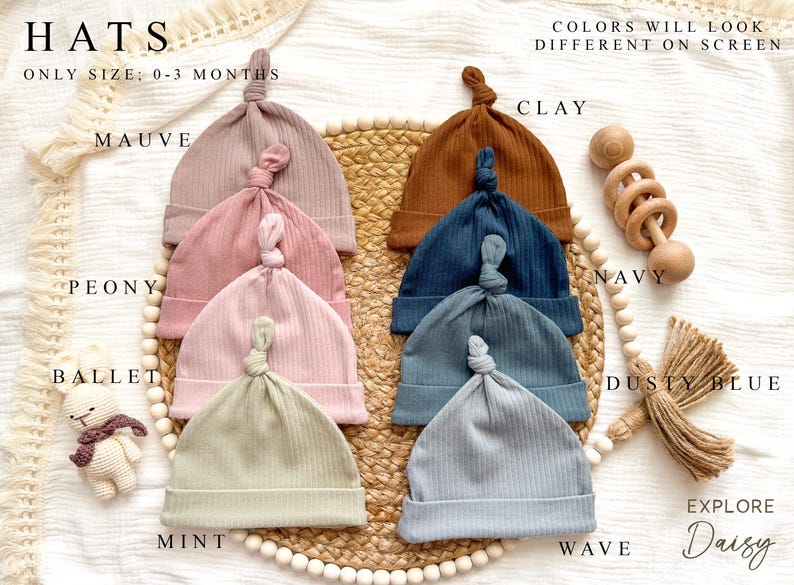 Peut inclure: Collection de bonnets pour b&eacute;b&eacute;s en tricot c&ocirc;tel&eacute;, disponibles en plusieurs couleurs, dont mauve, pivoine et menthe. Les bonnets sont pr&eacute;sent&eacute;s sur un tapis tress&eacute;, avec un hochet en bois et un petit jouet. Le texte indique "HATS" et "ONLY SIZE: 0-3 MONTHS".