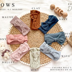 Peut inclure: Divers bandeaux pour b&eacute;b&eacute;s de couleurs vari&eacute;es, notamment mauve, argile, marine et menthe, pr&eacute;sent&eacute;s sur un tapis tiss&eacute;. Le texte "BOWS" et "EXPLORE Daisy" est visible. Ces bandeaux sont con&ccedil;us pour les b&eacute;b&eacute;s de 0 &agrave; 3 mois.