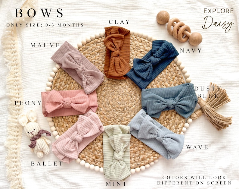 Peut inclure: Divers bandeaux pour b&eacute;b&eacute;s de couleurs vari&eacute;es, notamment mauve, argile, marine et menthe, pr&eacute;sent&eacute;s sur un tapis tiss&eacute;. Le texte "BOWS" et "EXPLORE Daisy" est visible. Ces bandeaux sont con&ccedil;us pour les b&eacute;b&eacute;s de 0 &agrave; 3 mois.