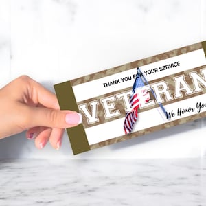 May include: A brown and white card with a camouflage pattern and the words "Thank you for your service Veteran We Honor You!"  The card has a small American flag on it.