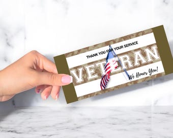 Peut inclure: Une carte marron et blanche avec un motif de camouflage et les mots "Thank you for your service Veteran We Honor You!" La carte a un petit drapeau américain dessus.