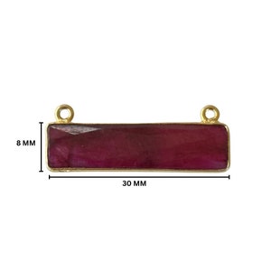 May include: A gold-plated bar pendant with a rectangular, deep red gemstone. The pendant measures 30 mm in length and 8 mm in width.