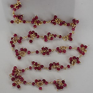 Puede incluir: Un collar de cadena de oro con pequeños colgantes en forma de flor rosa. El collar está hecho de una cadena de oro delicada y presenta múltiples colgantes en forma de flor rosa.