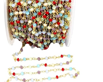 May include: A spool of gold chain with multi-colored glass beads. The beads are in shades of red, blue, green, and beige. The chain is perfect for making jewelry.
