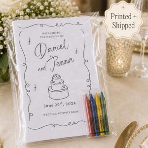 May include: A white wedding activity book in a clear plastic sleeve with four crayons. The cover features black text reading Welcome to the wedding of Daniel and Jenna, June 29th, 2024, Wedding Activity Book, and a line drawing of a three-tier cake.