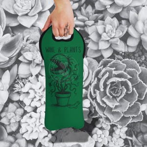 Peut inclure: Un sac isotherme vert pour bouteille de vin avec une poignée noire et le texte "Wine & Plants" imprimé sur le devant. Le sac isotherme présente une illustration en noir et blanc d'une plante carnivore.